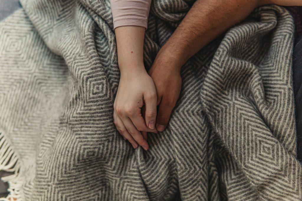 Pareja cogida de la mano sobre una manta, terapia de pareja online